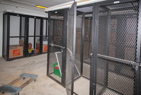 A room with a metal gate and a green bucket inside.
