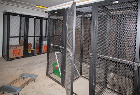 A room with a metal gate and a green bucket inside.