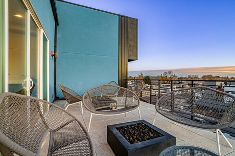 A patio with a table, chairs and a fire pit.