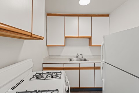A white kitchen with a stove and sink.