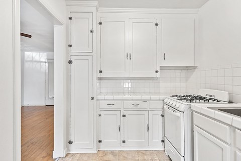 A kitchen with white cabinets and a white stove.