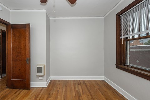 A room with a wooden door and a window with blinds.