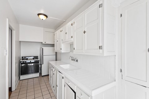 A kitchen with white cabinets and appliances.