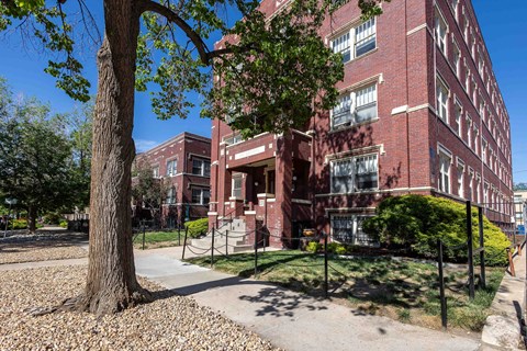 A red brick building with a tree in front of it.