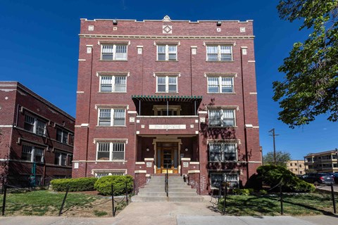 A red brick building with a green roof and a white door.