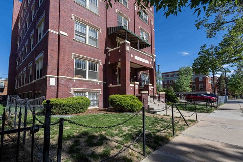 A red brick building with a black fence in front.