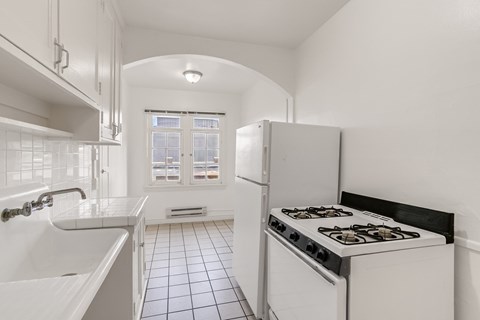 A white kitchen with a stove and a sink.
