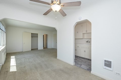 A spacious room with a ceiling fan and a cabinet.