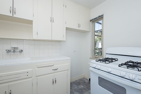 A white kitchen with a stove and cabinets.