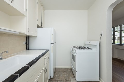 A white kitchen with a stove and sink.
