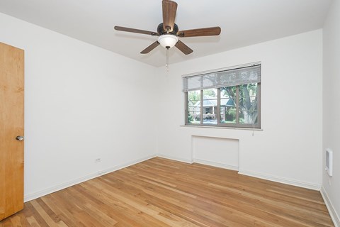A room with a ceiling fan and a window with blinds.