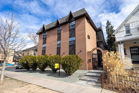 A red brick building with a black gate in front.