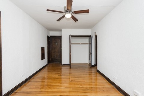A room with a ceiling fan and wooden floors.