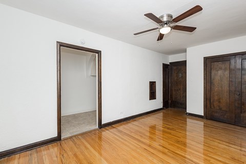 A room with a ceiling fan and a wooden floor.