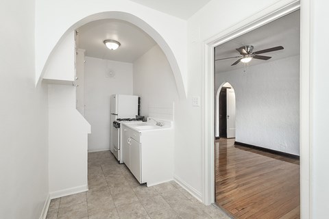 A white kitchen with a refrigerator, dishwasher, and a ceiling fan.