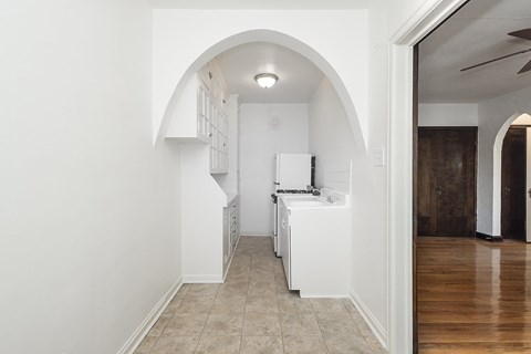 A white kitchen with a refrigerator, sink, and cabinets.