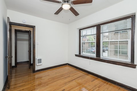 A room with a ceiling fan and a window with blinds.