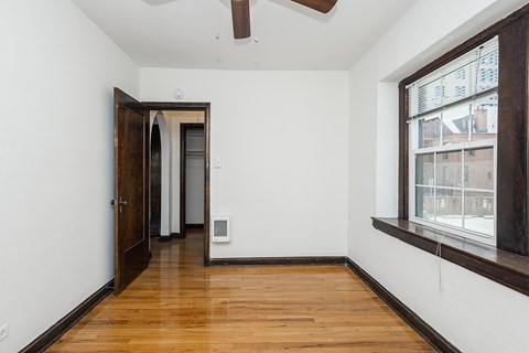 A room with a wooden floor and a window on the right side.