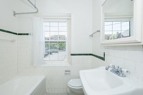 A white bathroom with a toilet, sink, and tub.