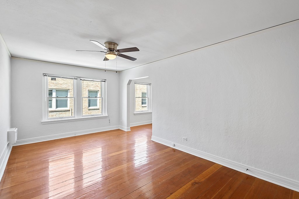 A room with a ceiling fan and wooden floors.