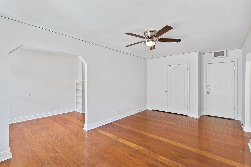 A room with a ceiling fan and wooden floors.