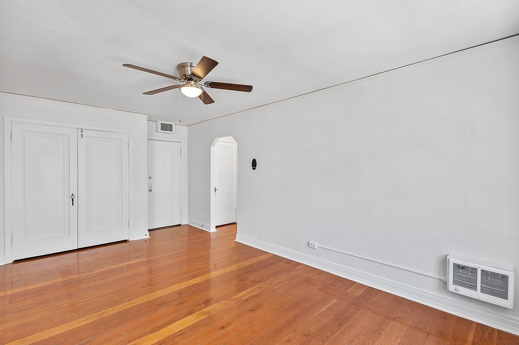 A room with a ceiling fan and a wood floor.