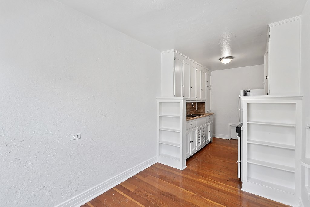 A kitchen with white cabinets and a wooden floor.