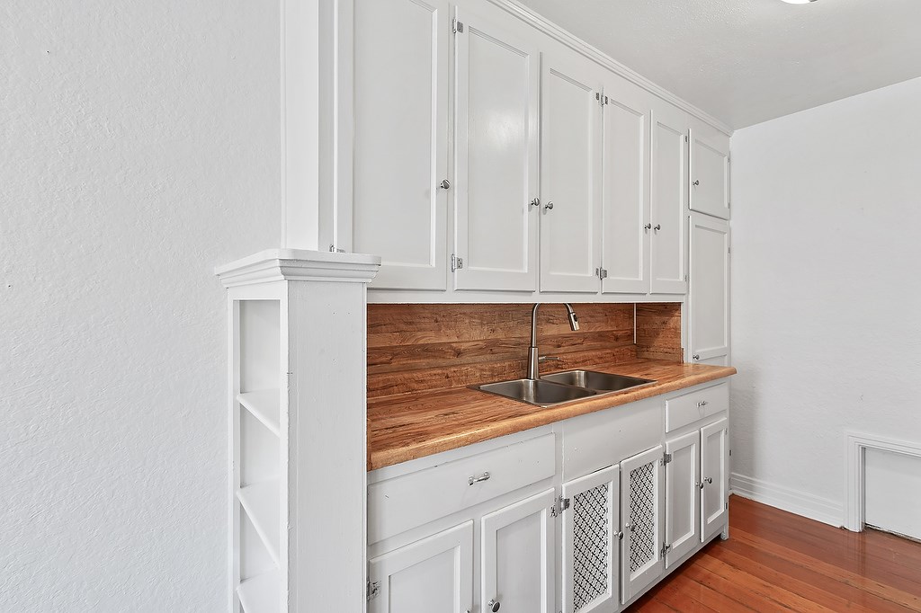 A kitchen with white cabinets and a wooden countertop.