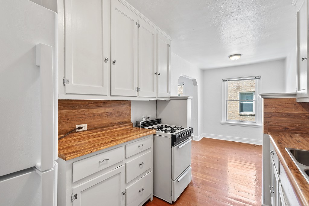 A kitchen with white cabinets and a wooden countertop.