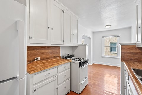 A kitchen with white cabinets and a wooden countertop.