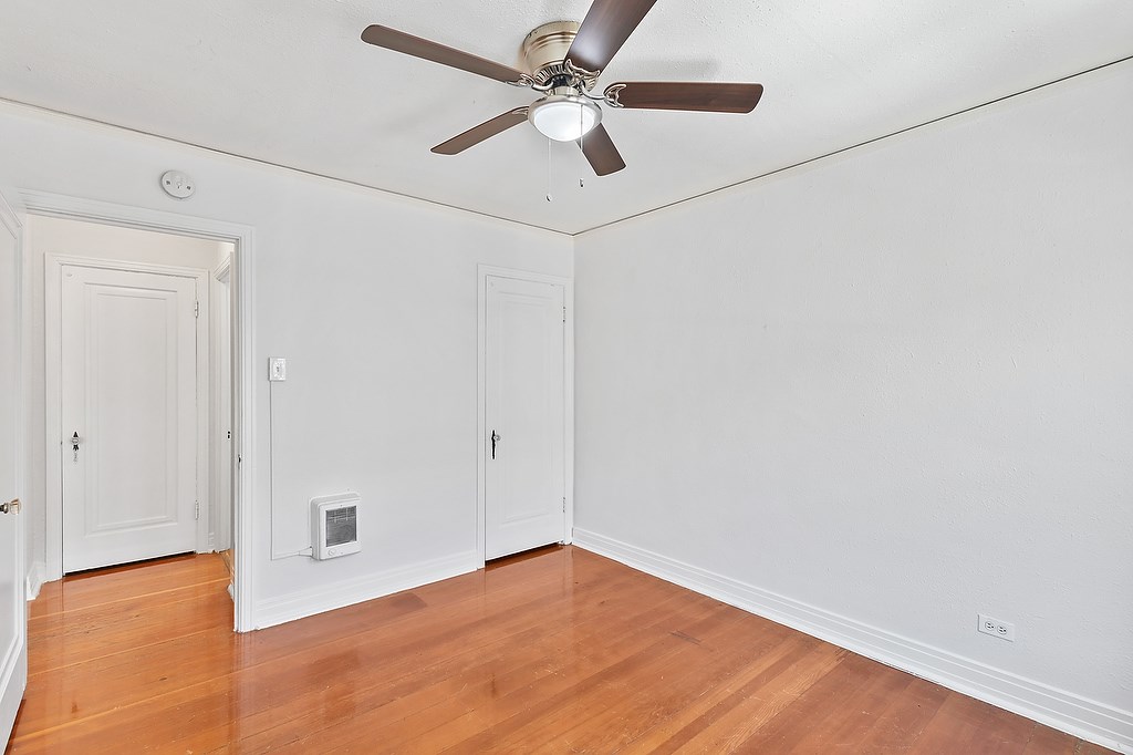 A room with a ceiling fan and wooden floors.