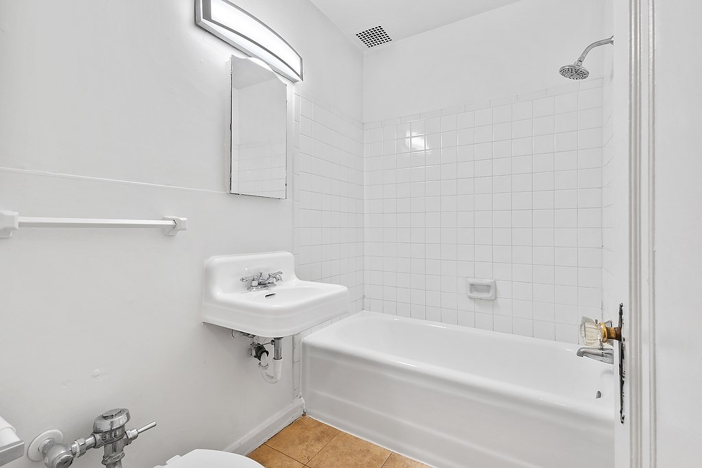 A white bathroom with a tub, toilet, and sink.