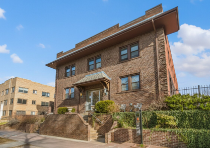 A large house with a brown brick exterior and a grey roof.