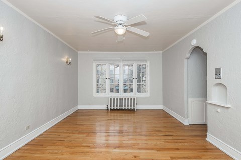 A room with a ceiling fan and a window with a view of a city.