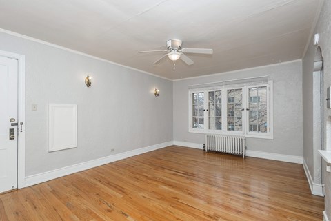 A room with a ceiling fan and a window with a view of a city.
