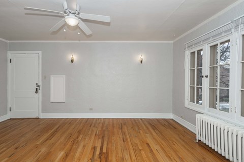 A room with a ceiling fan and a radiator on the floor.