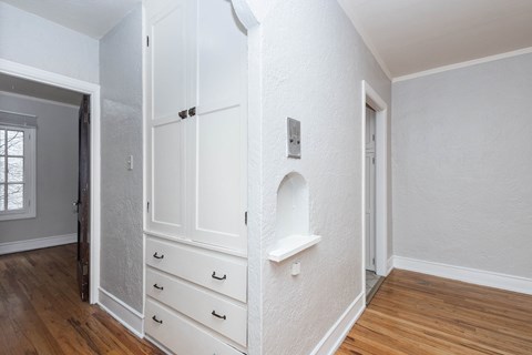 A white wall with a shelf and a door.