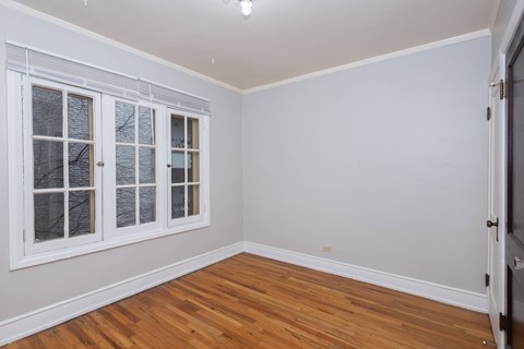 A room with a wooden floor and white walls with a window.