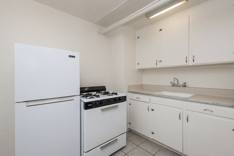 A white fridge and stove in a kitchen with white cabinets.