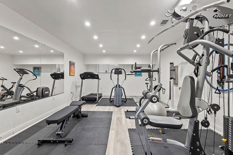 A gym with a variety of equipment including a treadmill, weights, and a bench.