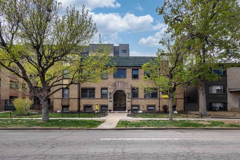 A building with a green roof and a tree in front of it.