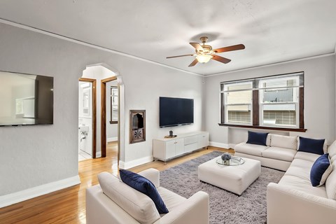 A living room with a white couch and a ceiling fan.