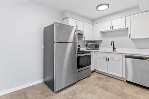 a white kitchen with stainless steel appliances and white cabinets