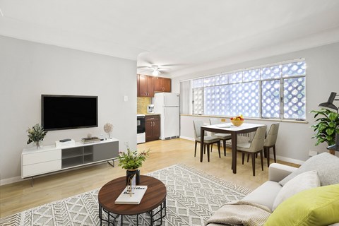 A living room with a television, a coffee table, and a dining table.