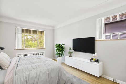 A bedroom with a bed, a television, and a window.