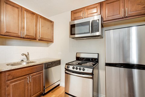 A kitchen with a stove, refrigerator, and microwave.