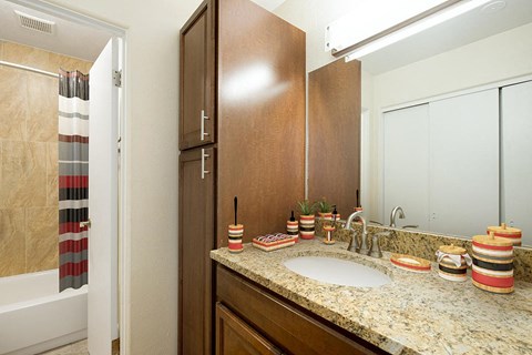 A bathroom with a sink, mirror, and cabinets.