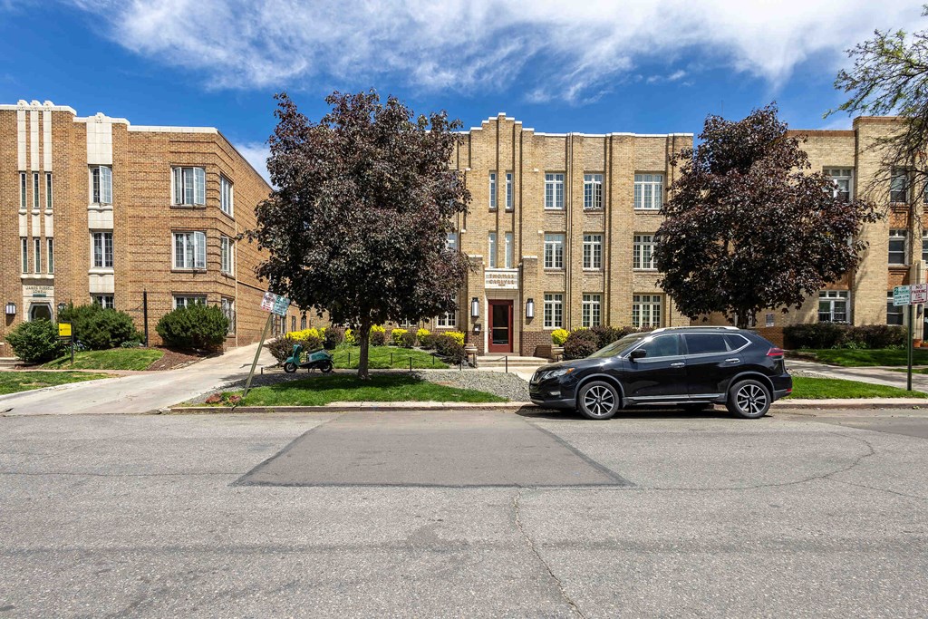 A black car is parked in a parking lot in front of a building.