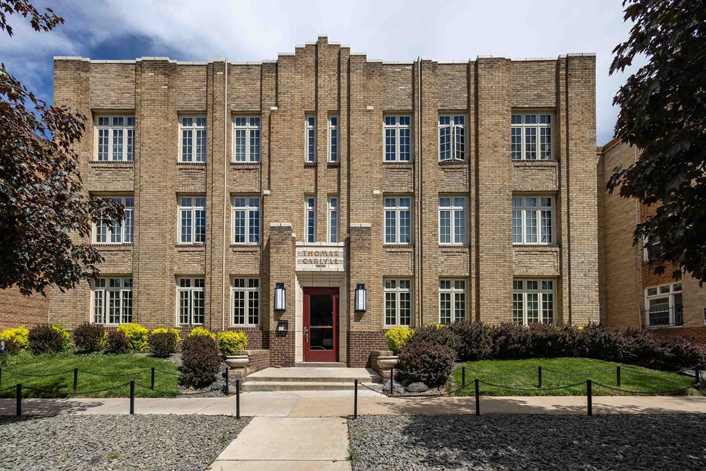 A large brick building with a red door and windows.