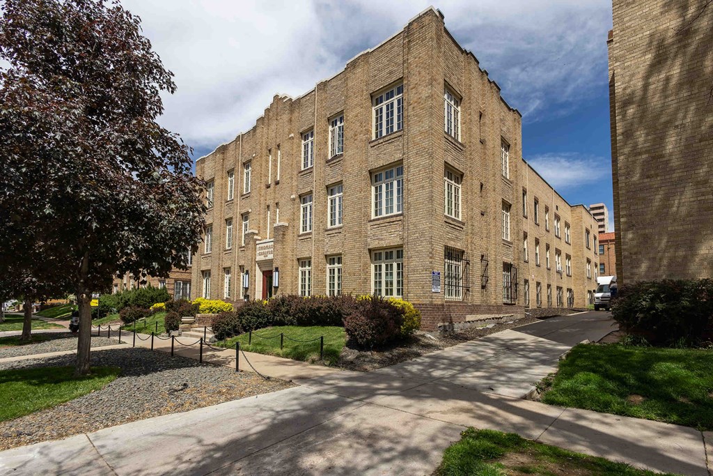 A large brick building with a tree in front of it.